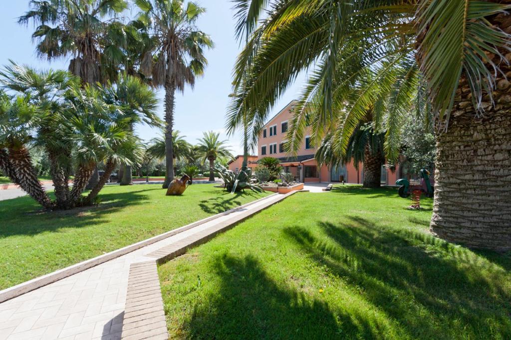 un parc avec des palmiers et un bâtiment dans l'établissement Villa Luigi Hotel & Restaurant Nuova gestione, à Martinsicuro