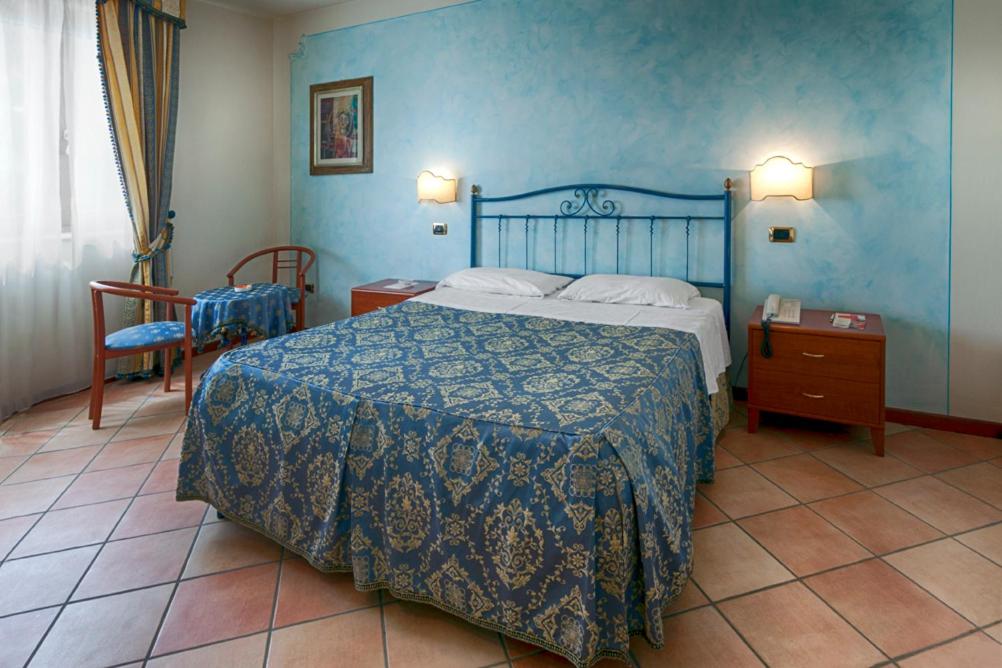 une chambre avec un lit et un mur bleu dans l'établissement Villa Luigi Hotel & Restaurant Nuova gestione, à Martinsicuro