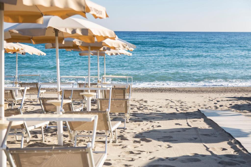 - une plage avec des tables, des chaises et des parasols dans l'établissement Hotel Village Paradise, à Mandatoriccio Marina 15 autres photos