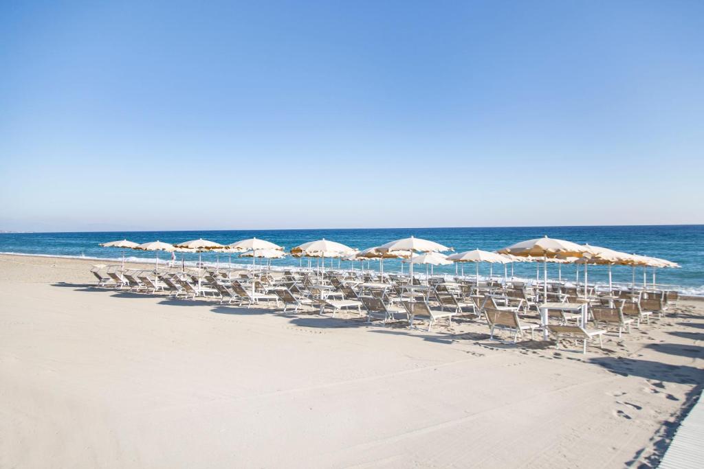 un groupe de chaises et de parasols sur une plage dans l'établissement Hotel Village Paradise, à Mandatoriccio Marina
