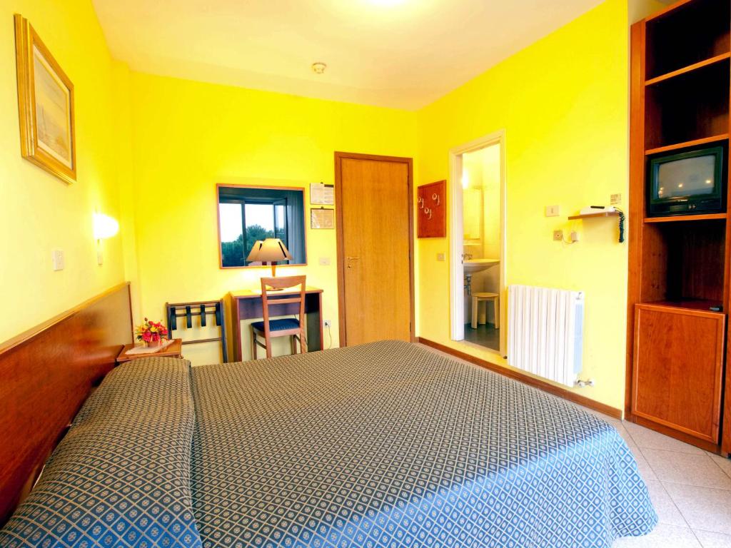 - une chambre avec un lit dans une pièce jaune dans l'établissement Hotel Capri, à Diano Marina