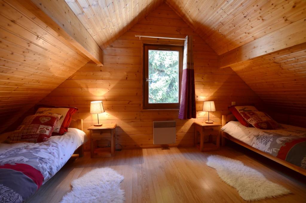 une chambre avec deux lits dans une cabane en rondins dans l'établissement Chalet de la Grimpette au coeur de Gérardmer, à Gérardmer