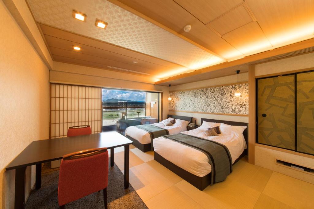 Cette chambre comprend 2 lits, une table et une télévision. dans l'établissement Juhachiro, à Gifu 44 autres photos