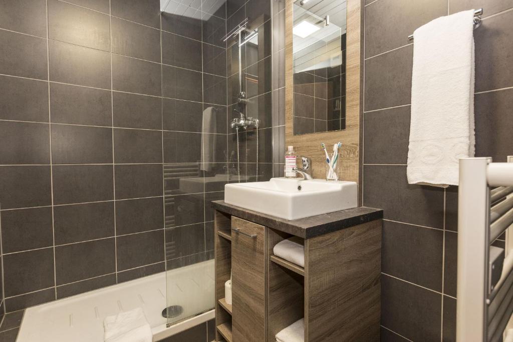 une salle de bain avec un lavabo, une douche et une baignoire dans l'établissement Résidence Odalys Le Front de Neige, aux Carroz d'Arâches 20 autres photos