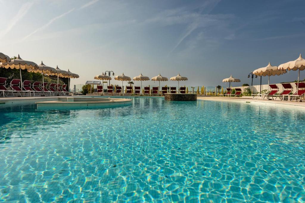 une grande piscine avec chaises et parasols dans l'établissement Baia del Mar Beach Boutique Hotel, à Lido di Jesolo