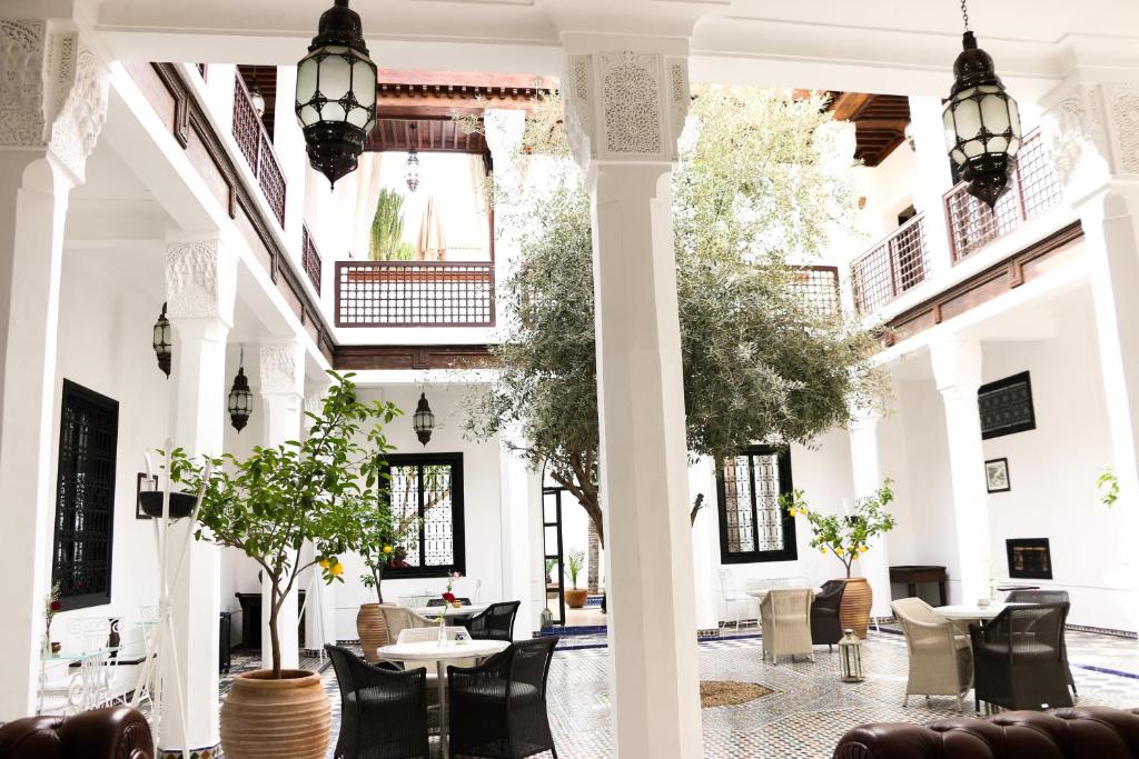 un hall avec des tables, des chaises et des arbres dans l'établissement Riad Bellamane Marrakech, à Marrakech