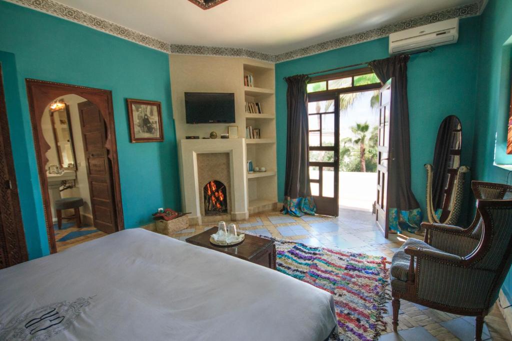 - une chambre avec un grand lit et une cheminée dans l'établissement Riad El Arsat & Spa, à Marrakech