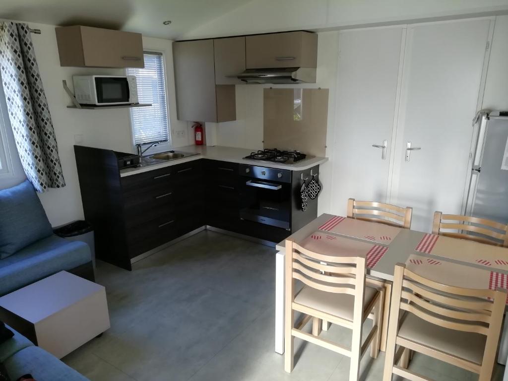 une cuisine avec une table et des chaises dans une pièce dans l'établissement Les Dunes de Contis 4 étoiles, à Saint-Julien-en-Born