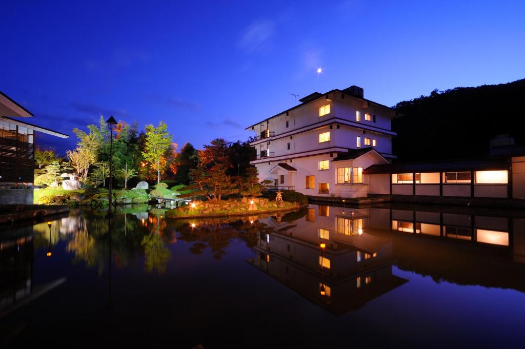 une maison avec des lumières dans l'eau la nuit dans l'établissement Onogawa Onsen Kajikaso, à Yonezawa