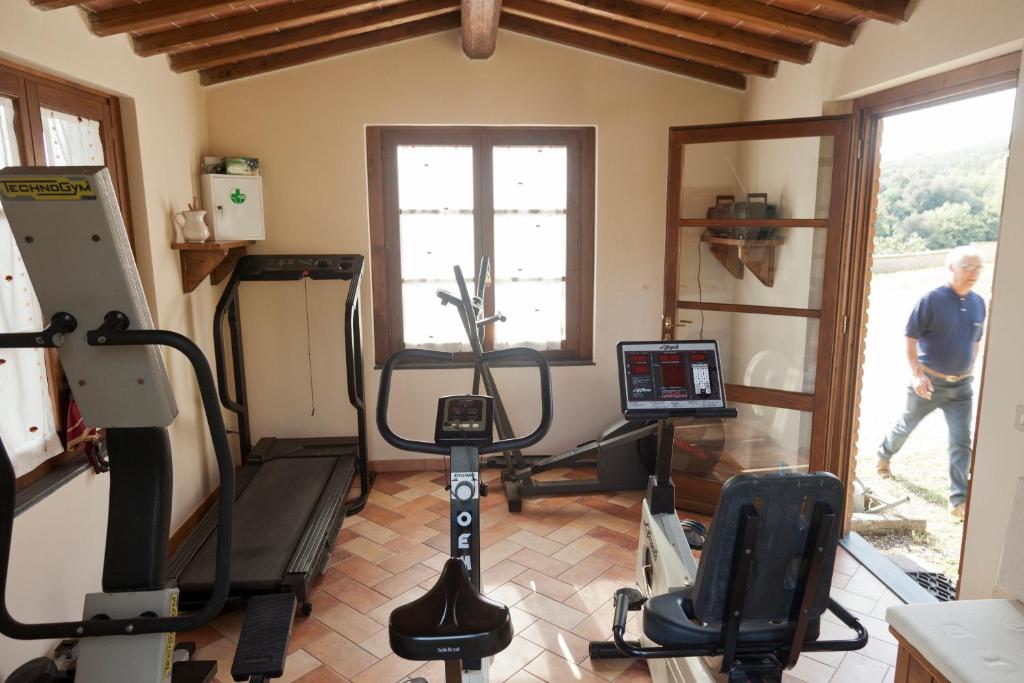 une salle de sport avec un homme marchant près d'une fenêtre dans l'établissement Villa Pilar in Toscana con piscina ultrapanoramica, à Montevettolini