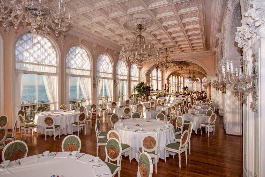 une salle de banquet avec des tables et des chaises blanches et des lustres dans l'établissement Hotel Excelsior Venice, sur le Lido de Venise 133 autres photos