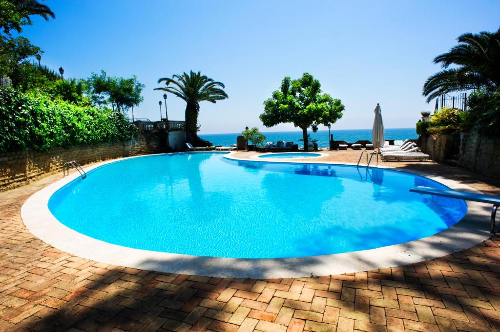 une grande piscine bleue avec l'océan en arrière-plan dans l'établissement Grande Albergo Miramare, à Formia