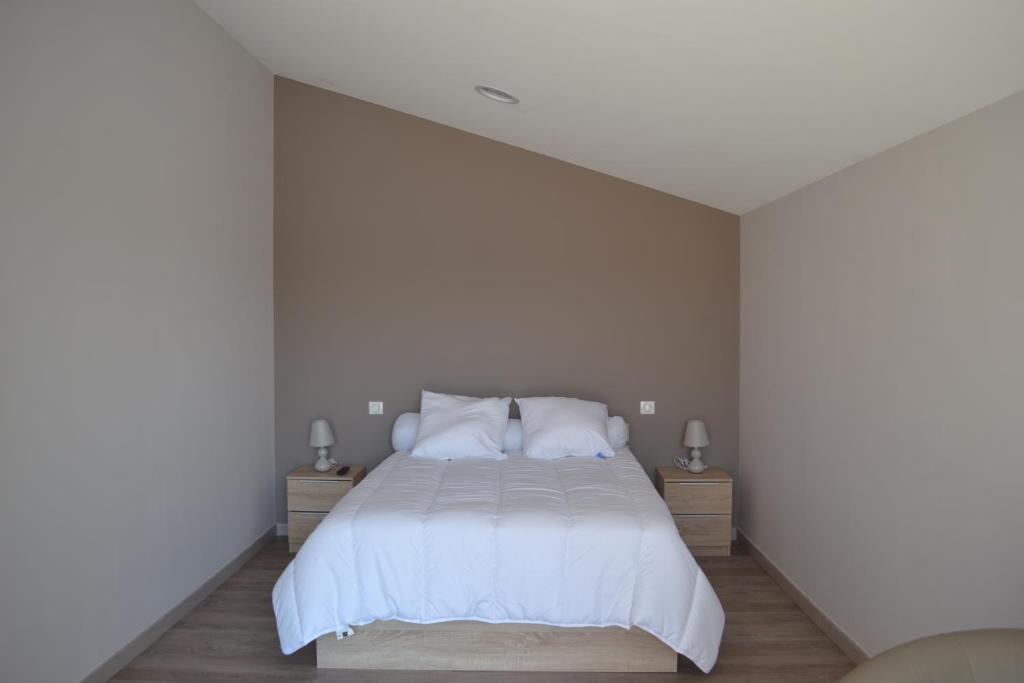 une chambre avec un lit blanc avec deux tables de nuit dans l'établissement Gîte du Béarnais, à Vanxains