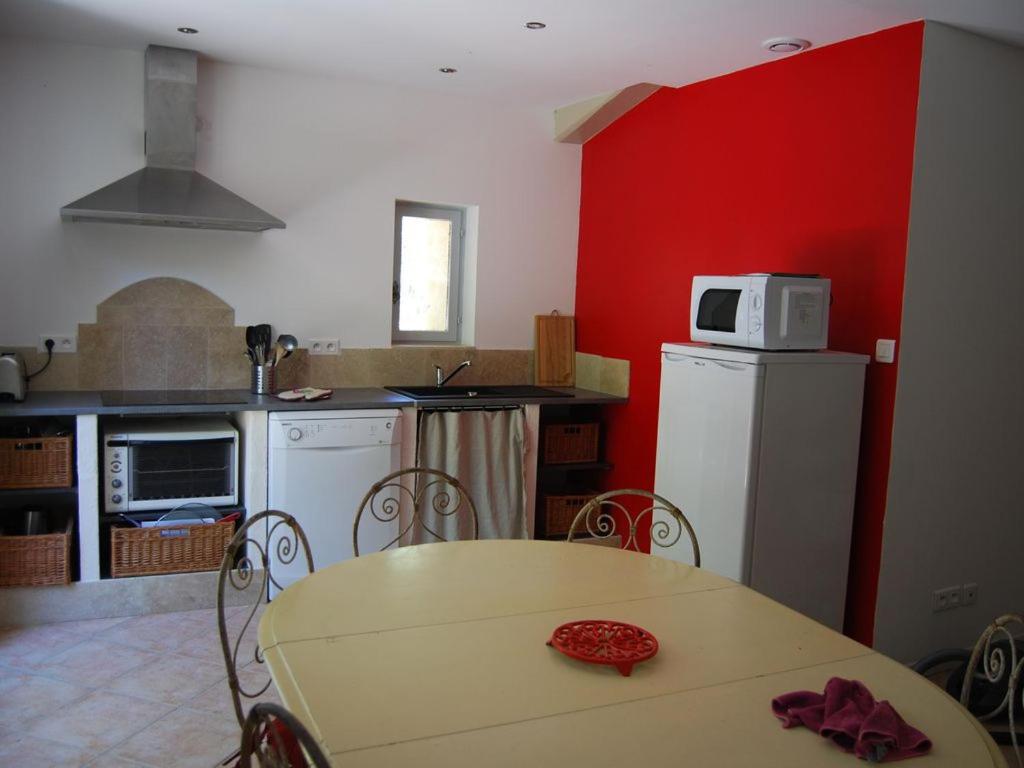 une cuisine avec une table et un réfrigérateur blanc dans l'établissement gite dentelles, à Loriol-du-Comtat
