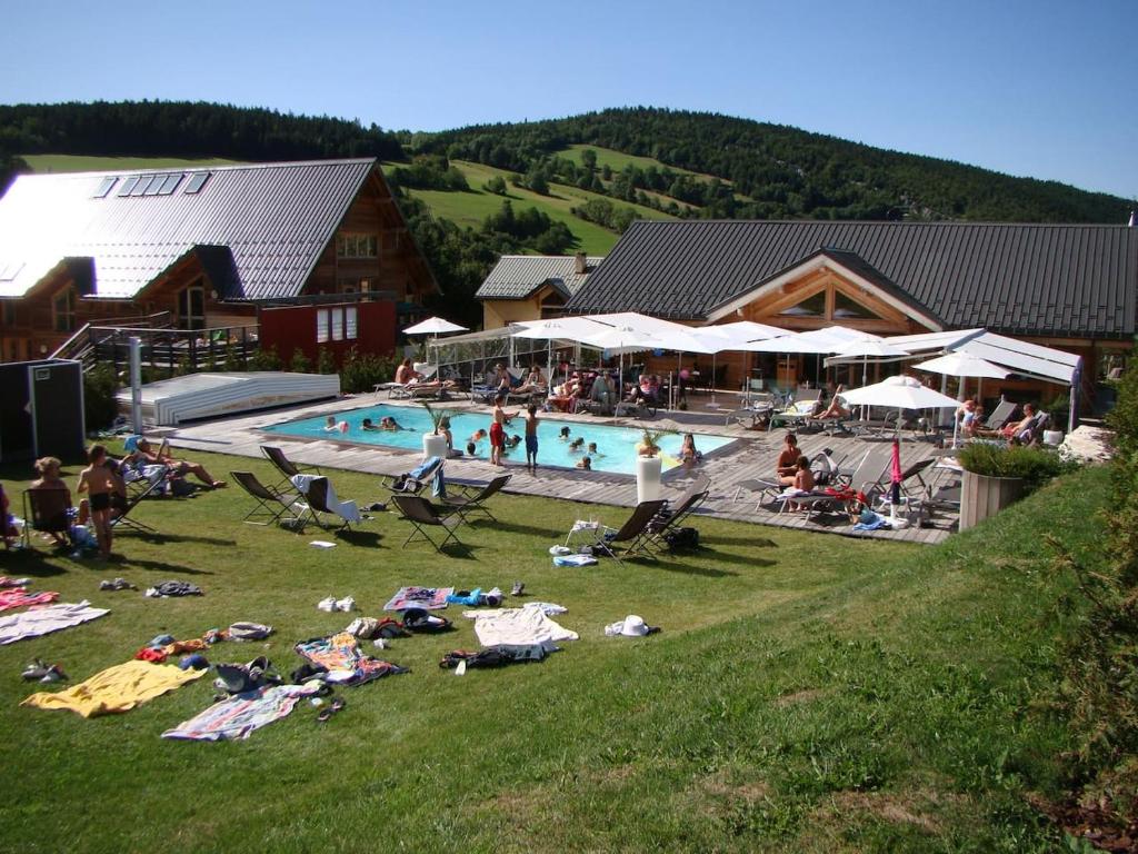Un groupe de personnes se posant dans l'herbe près d'une piscine dans l'établissement Les Sens Ciel, à Corrençon-en-Vercors