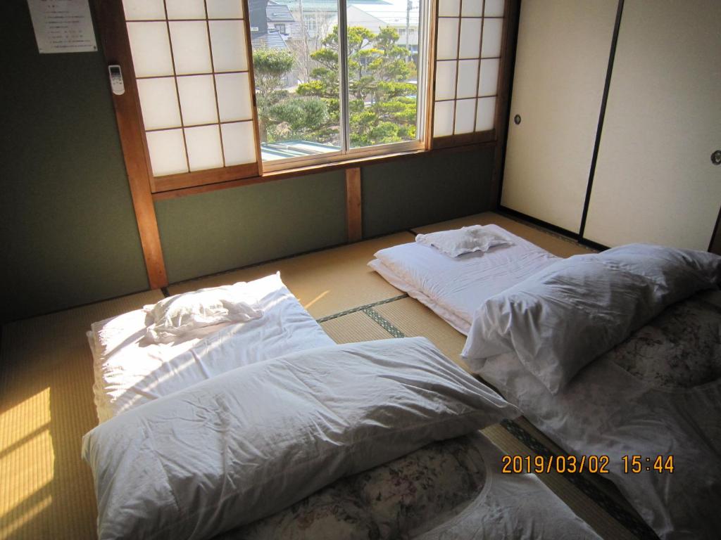 deux lits dans une chambre avec deux fenêtres dans l'établissement Minshuku Kobayashi, à Narusawa