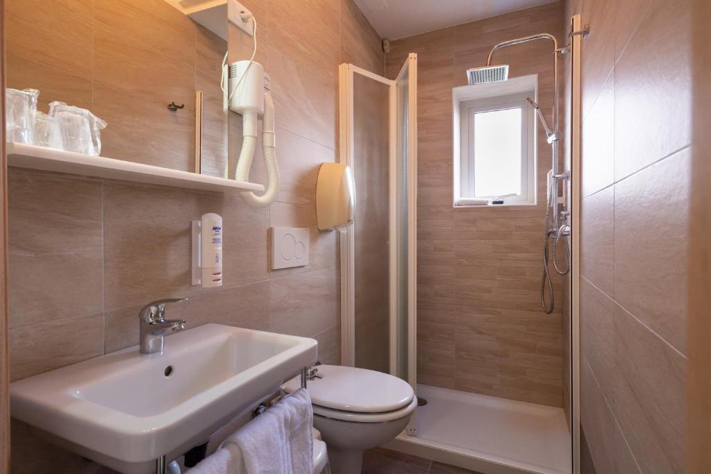 une salle de bain avec un lavabo et des toilettes dans l'établissement Hotel Atenea Golden Star, à Caorle