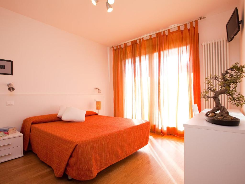 - une chambre avec un lit doté d'une couverture orange et d'une fenêtre dans l'établissement Residence Speranza, à Lido di Jesolo