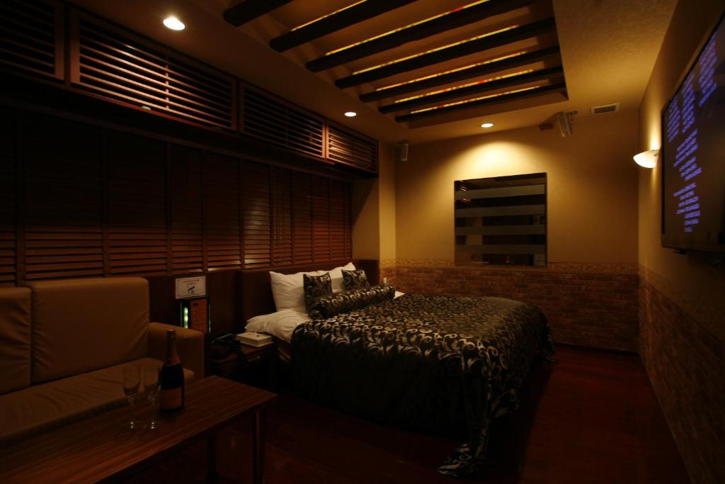 une chambre avec un lit, un canapé et une télévision dans l'établissement ホテルパシオン, à Hamano