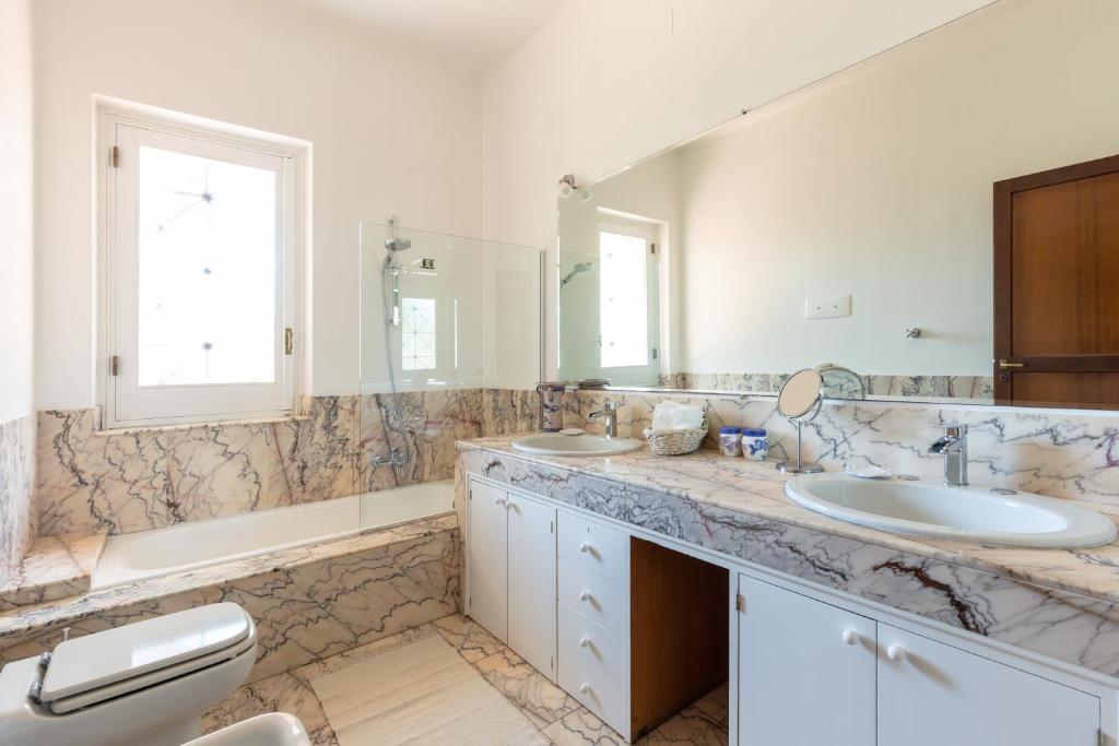 une salle de bain avec deux lavabos et une baignoire et deux miroirs dans l'établissement Il Giardino di Michela by DomuSicily, à Mondello