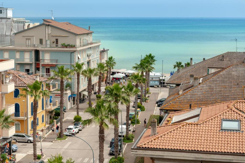 une rue de la ville avec des palmiers et l'océan dans l'établissement Hotel Mondial, à Porto Recanati