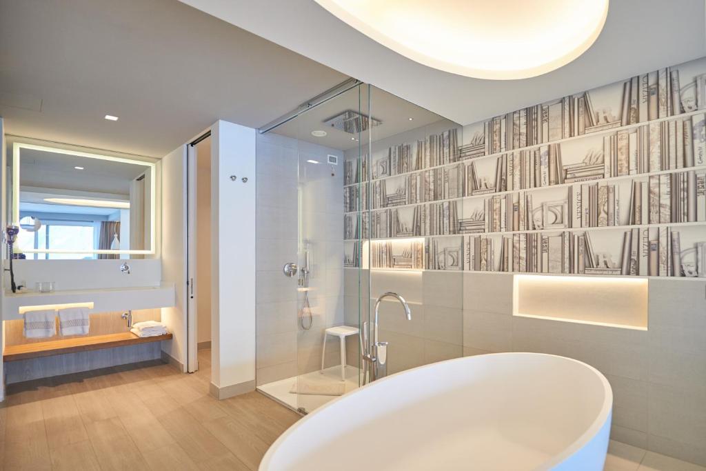 une salle de bain avec une baignoire et un mur avec des livres dans l'établissement Hotel Castello Lake Front, à Malcesine