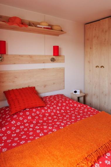 - une chambre avec un lit rouge et une couverture orange dans l'établissement La Drugère - Gîtes et Roulottes, à Nyons