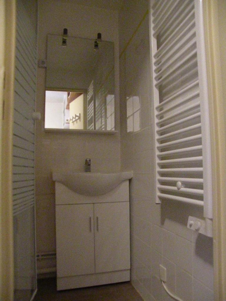 une salle de bain blanche avec un lavabo et un miroir dans l'établissement Au Coeur De La Station, à Les Deux Alpes