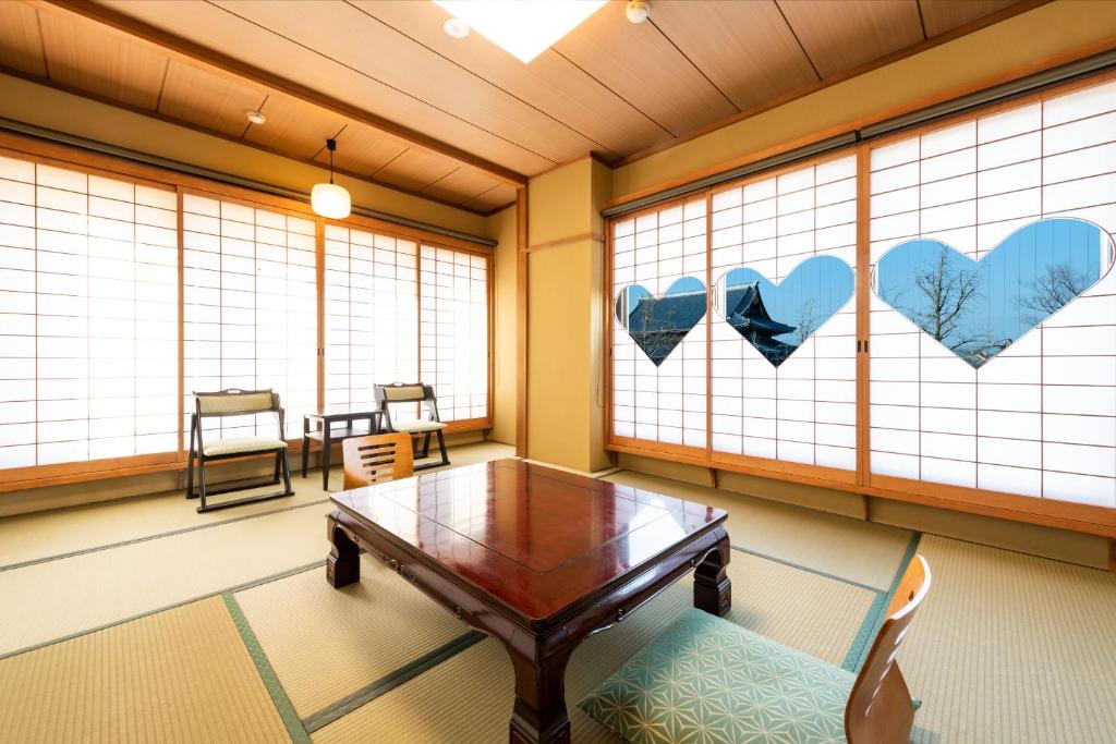 une pièce avec une table, des chaises et des fenêtres dans l'établissement Yamadaya Ryokan, à Kyoto