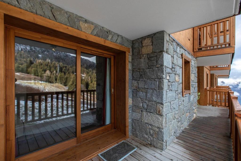 une chambre avec une grande porte en verre sur une terrasse dans l'établissement Arc 1800 Alpage du chantel Iseran SKI-in SKI-out, à Arc 1800 9 autres photos