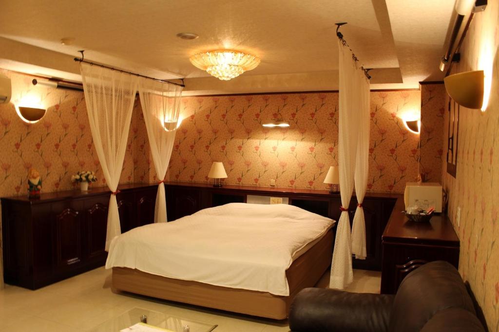 une chambre avec un lit et un canapé dans l'établissement Santa no Ouchi-LoveHotel, à Miyazaki