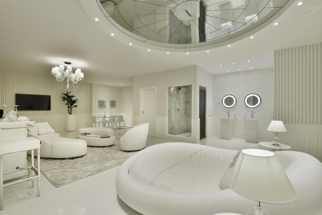 - une chambre blanche avec un grand lit et un salon dans l'établissement Hotel Ariston, à Paestum