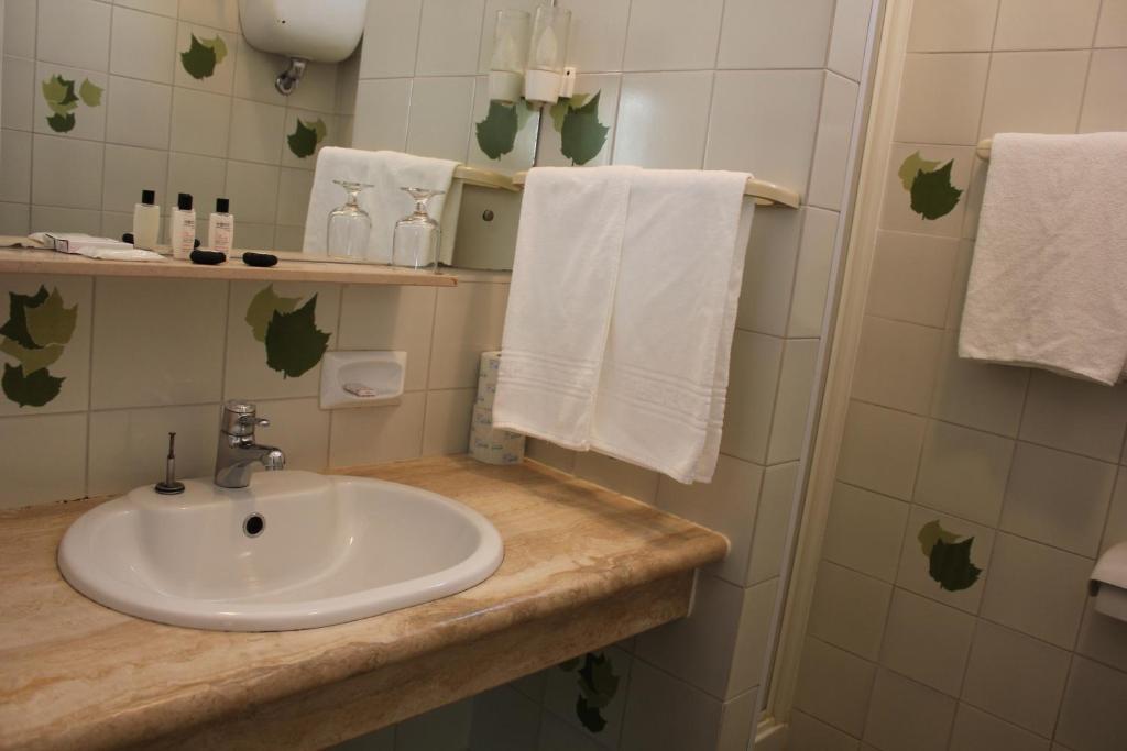 La salle de bains est pourvue d'un lavabo et de serviettes blanches. dans l'établissement Hotel Venezia New, à Vasto