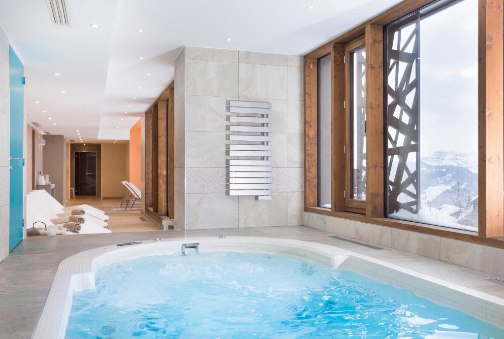 une baignoire jacuzzi dans une chambre avec fenêtres dans l'établissement Résidence Club MMV Les Chalets des Cimes, aux Saisies