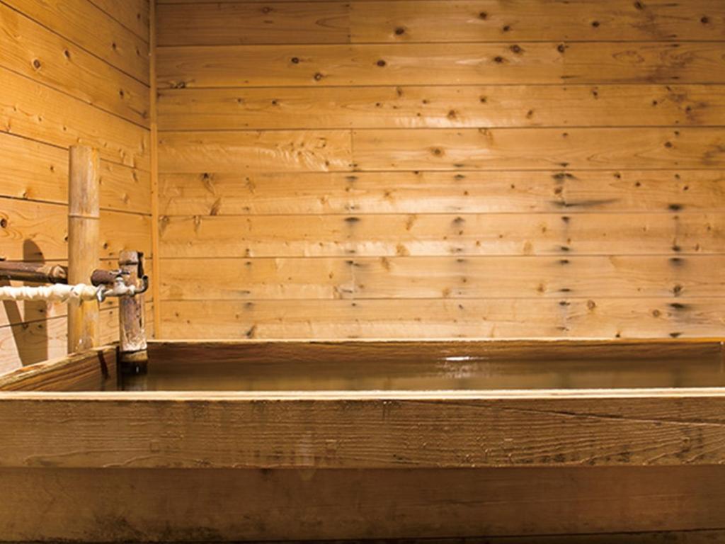 Cette chambre est dotée d'un mur en bois et d'une baignoire. dans l'établissement Ryuudo, à Minakami