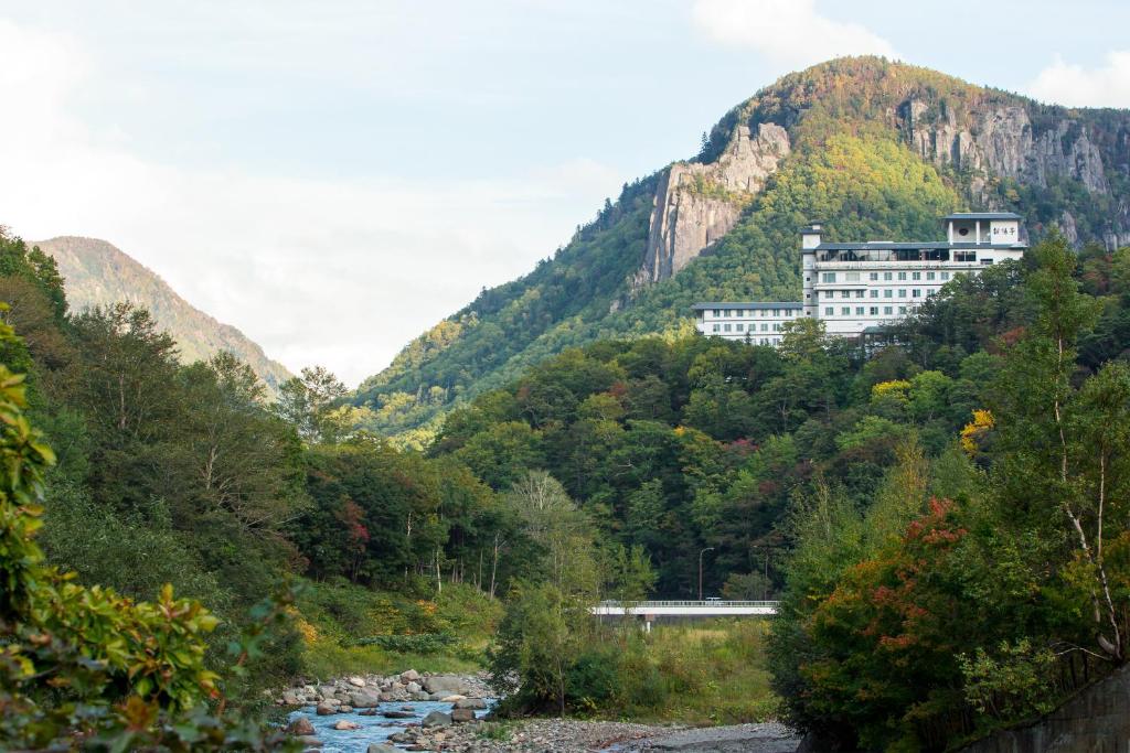 un bâtiment sur le flanc d'une montagne avec une rivière dans l'établissement Choyo Tei, à Kamikawa
