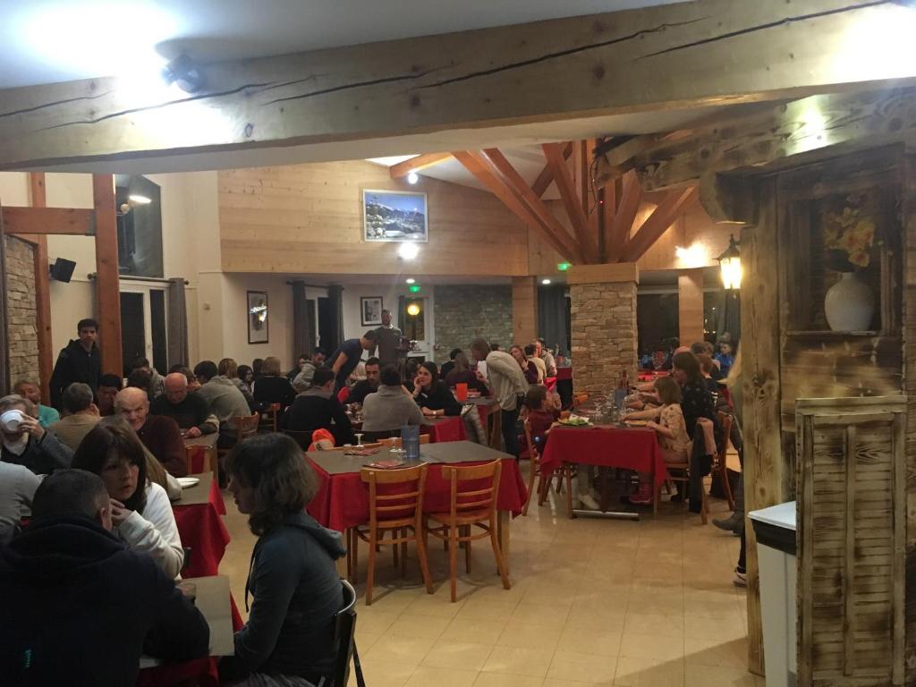 un groupe de personnes assises à des tables dans un restaurant dans l'établissement Hôtel Les Écrins, aux Orres