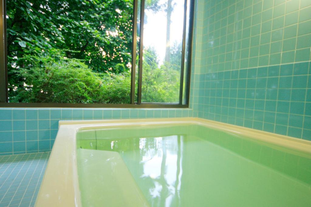 une baignoire dans une salle de bain avec une fenêtre dans l'établissement Nobori, à Ome