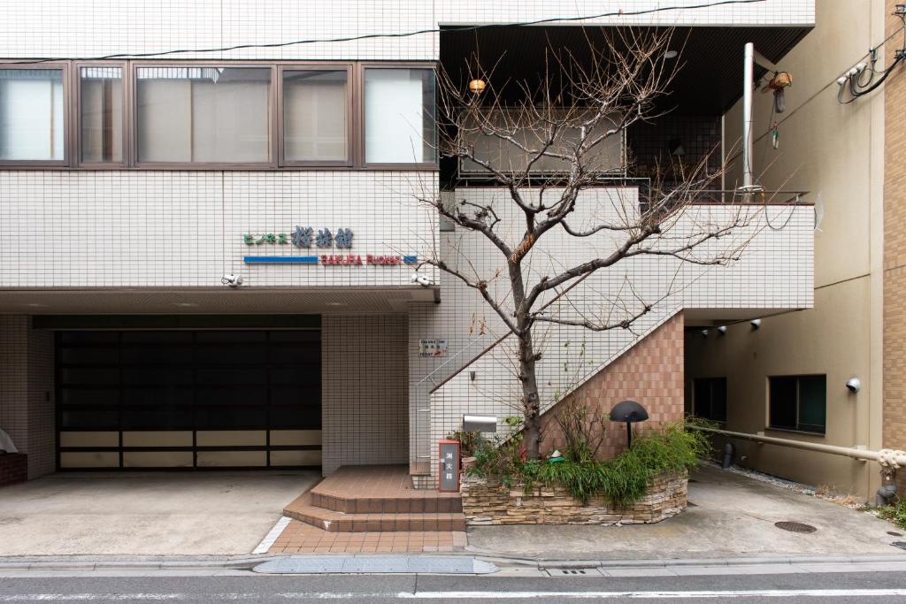un bâtiment avec un arbre devant lui dans l'établissement Sakura Ryokan Asakusa Iriya, à Tokyo