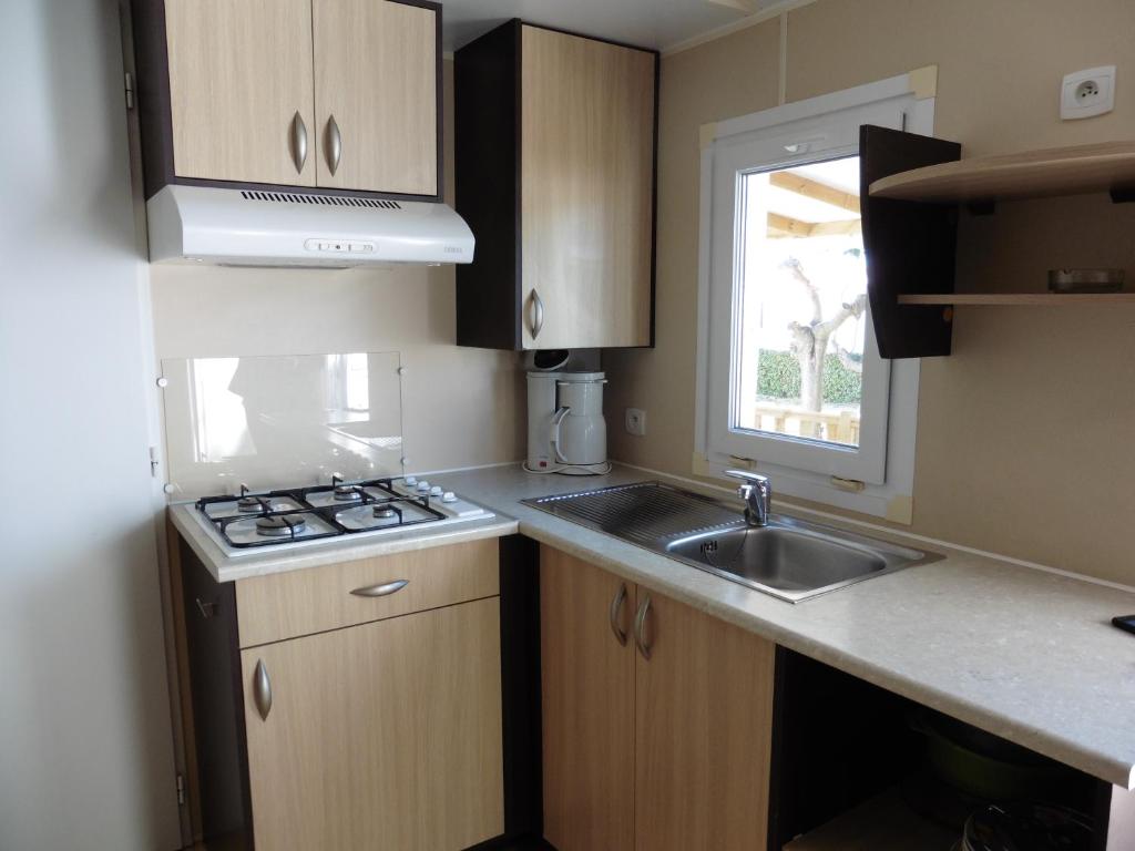 une petite cuisine avec un évier et une cuisinière dans l'établissement Mobil Home Méditerranée avec terrasse, à Vic-la-Gardiole