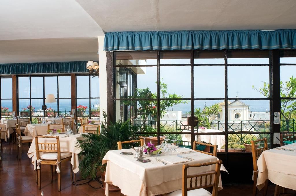 un restaurant avec des tables et des chaises et de grandes fenêtres dans l'établissement Hotel La Villarosa Terme, à Ischia