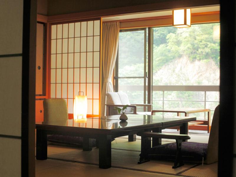 une pièce avec une table, des chaises et une fenêtre dans l'établissement Enraku, à Kurobe