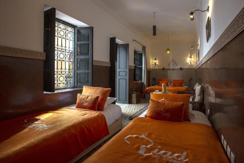 Cette chambre d'hôtel comprend 2 lits avec des draps orange. dans l'établissement Riad Ciel d'Orient, à Marrakech 37 autres photos