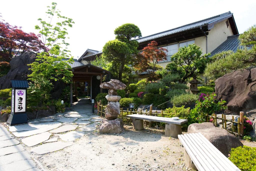 un jardin avec un banc en pierre et un bâtiment dans l'établissement Kikori, à Fuefuki