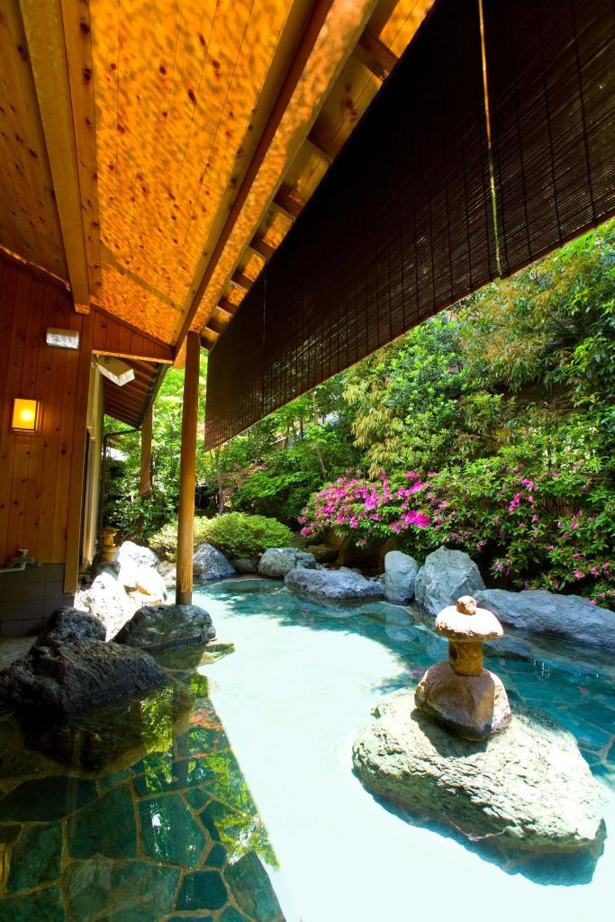 une piscine avec des rochers et une fontaine dans un jardin dans l'établissement Kikori, à Fuefuki