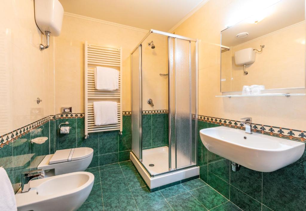 une salle de bain avec deux lavabos et une douche dans l'établissement Hotel Lido - Beach and Palace, à Bolsena
