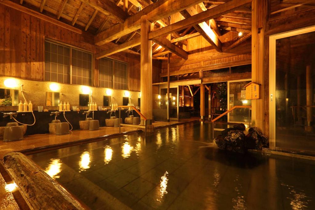 une piscine dans un grand bâtiment en bois avec des lumières dans l'établissement Hotel Futaba, à Yuzawa