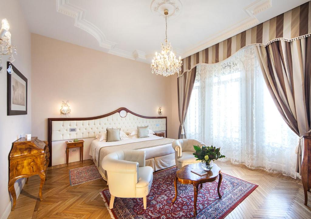 une chambre avec un grand lit et un lustre dans l'établissement Grand Hotel Rimini, à Rimini