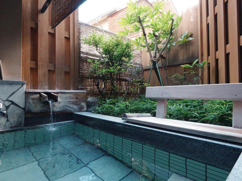 un jardin avec un banc et une fontaine dans l'établissement Shibu Onsen KOKUYA, à Yamanouchi