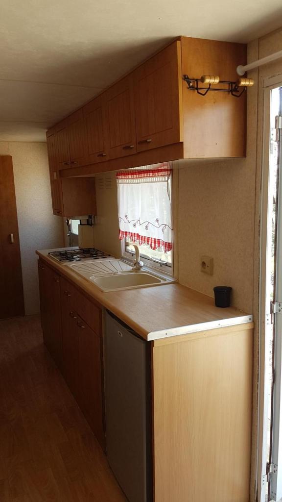 une cuisine avec des armoires en bois, un évier et une fenêtre dans l'établissement Mobil Home à la ferme, en Provence, à Grambois